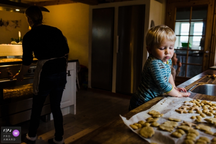 A little boy looks longingly at cookies cooling on the counter in this documentary-style family photo captured by a Copenhagen photographer. 