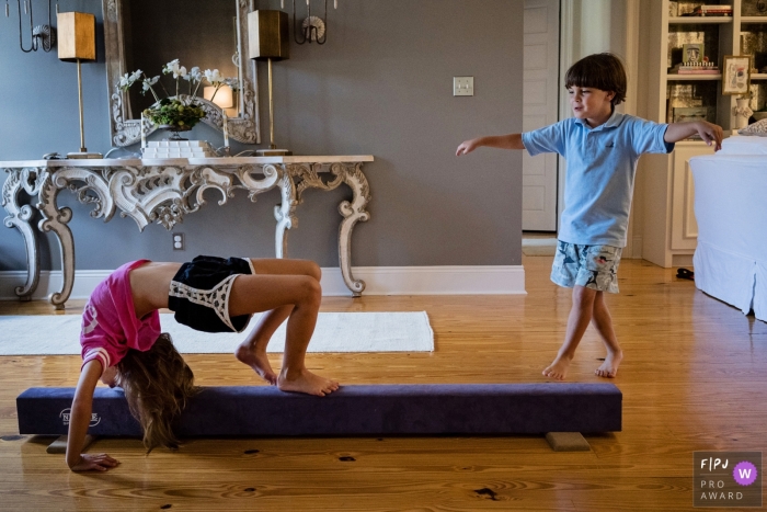 Photo by: <a href="https://www.fpja.com/documentary-family-photography-contests/julie-ambos/key-west/2086211">Julie Ambos - United States</a> A young boy imitates his sister as she practices on a balance beam in this photograph by a Key West, FL documentary family photographer.