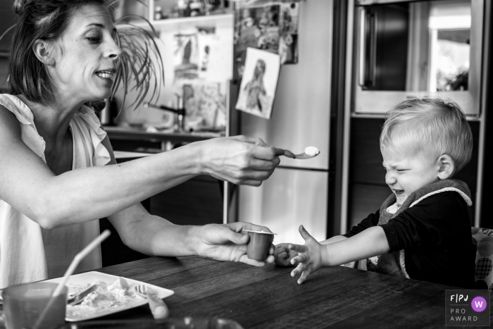 This black and white photo of a toddler refusing to eat his yogurt was captured by a North Rhine-Westphalia documentary family photographer