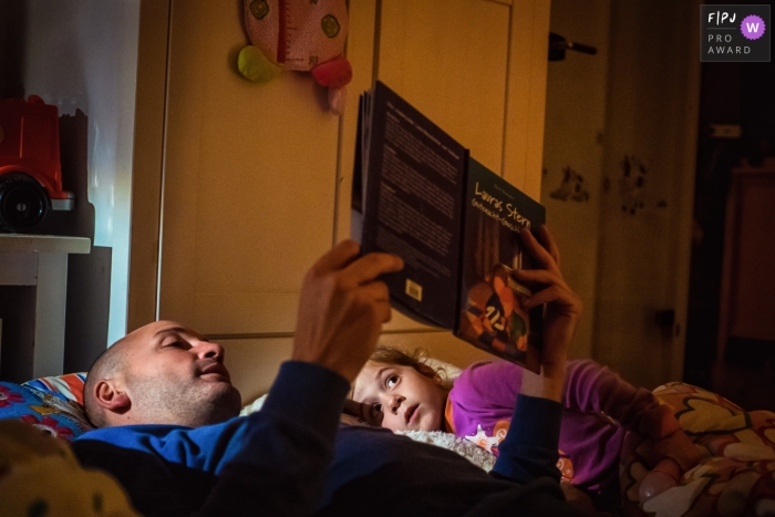 North Rhine-Westphalia documentary family photographer captured this photo of a father and daughter sharing a favorite story in bed