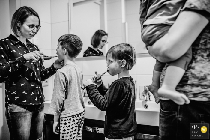 This black and white photo of a family brushing their teeth was captured by a Netherlands documentary family photographer