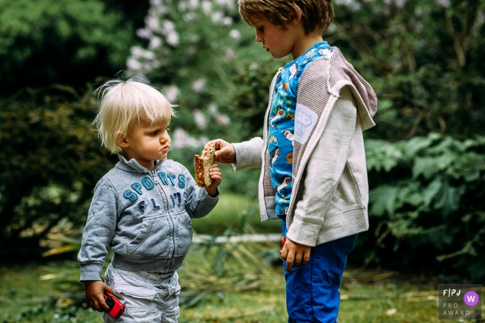 Le photographe de famille documentaire de Wallonie a capturé cette photo de deux frères partageant un sandwich dans la cour