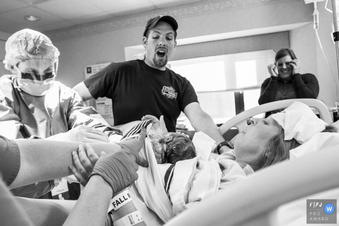Photo by: <a href="https://www.fpja.com/documentary-family-photography-contests/jayne-rohlfing/indiana/2088096">Jayne Rohlfing - United States</a> Indiana documentary family photographer captured this black and white photo of a fathers surprised look as his newborn baby is laid on his partners chest