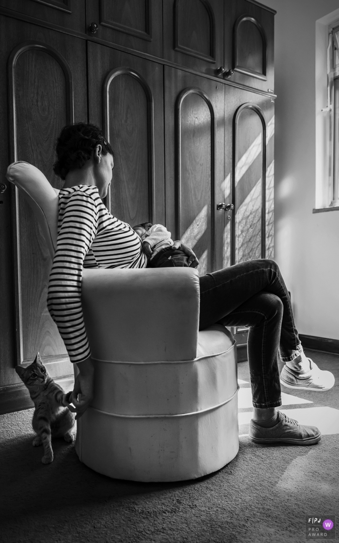 Photo by: <a href="https://www.fpja.com/documentary-family-photography-contests/nina-castro/belem/2088541">Nina Castro - Brazil</a> Para documentary style family photographer captured this black and white photo of a quiet moment as a mother nurses the baby and plays with the family cat