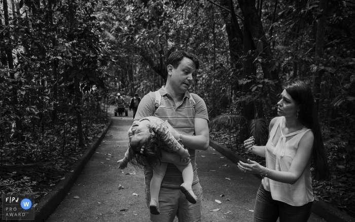 Para documentary family photographer captured this black and white photo of a father carrying a tired toddler out of the park as her mother walks nearby