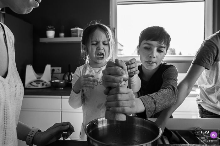 This black and white photo of a brother and sister fighting over who gets to use the salt shaker was captured by a Auvergne-Rhone-Alpes documentary family photographer