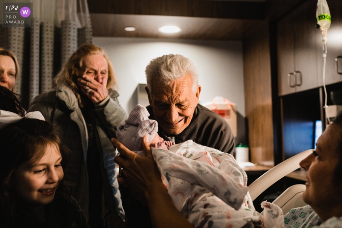 Le photographe de famille documentaire de Pittsburgh saisit cette photo de fiers grands-parents qui rencontrent le petit-enfant pour la première fois lors d'une naissance à l'hôpital