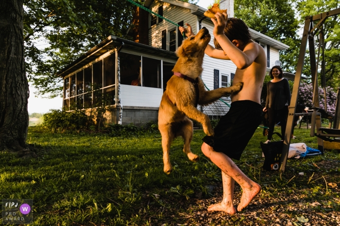 Photo by: <a href="https://www.fpja.com/documentary-family-photography-contests/pamela-anticole/pittsburgh/2089046">Pamela Anticole - United States</a> Pittsburgh documentary family photographer captured this photo of a dog trying to steal his young owners pizza while playing in the yard