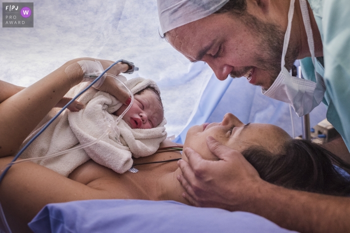 Photo by: <a href="https://www.fpja.com/documentary-family-photography-contests/clara-sampaio/rio-de-janeiro/2089126">Clara Sampaio - Brazil</a> This photo of a father gazing lovingly at his partner as their newborn child sleeps on her chest was captured by a Brazil documentary family photographer