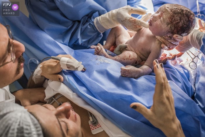 Photo by: <a href="https://www.fpja.com/documentary-family-photography-contests/clara-sampaio/rio-de-janeiro/2089136">Clara Sampaio - Brazil</a> A mother and father stare at their newborn baby in this hospital birthing photo captured by a Brazil documentary family photographer