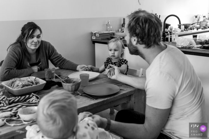 Le photographe de famille documentaire d'Émilie-Romagne a capturé cette photo en noir et blanc d'une famille disant grâce avant le dîner