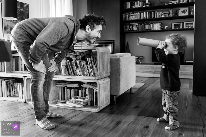 A little boy looks at his father through a cardboard tube in this FPJA award-winning picture by a Modena family photographer.