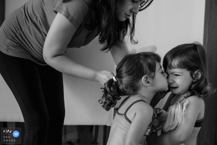 A little girl kisses her sister to comfort her while she cries in this photograph created by a Minas Gerais family photojournalist. 