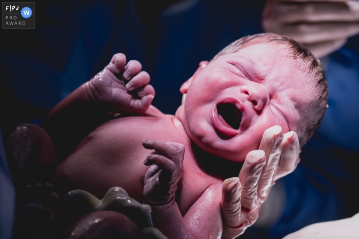 Photo by: <a href="https://www.fpja.com/documentary-family-photography-contests/ana-paula-faria/s%C3%A3o-paulo/2089901">Ana Paula Faria - Brazil</a> A nurse holds a newborn baby right after a hospital birth in this photo composed by a Sao Paulo, Brazil award-winning photographer.