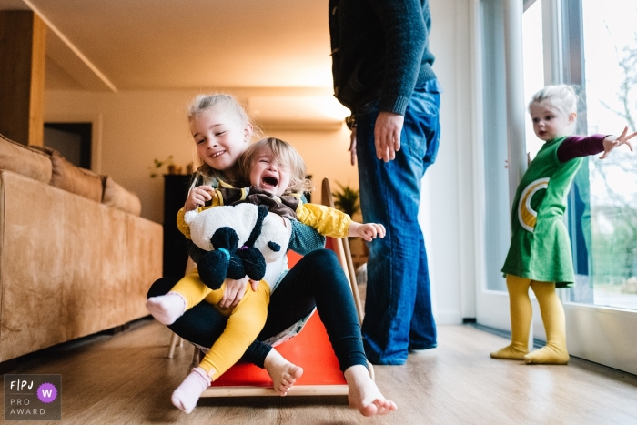 Photo by: <a href="https://www.fpja.com/documentary-family-photography-contests/annemarie-rikkers/gelderland/2090016">Annemarie Rikkers - Netherlands</a> A little girl gets upset when her sister holds her as they go down a slide in this image created by a Gelderland, Netherlands family photographer.
