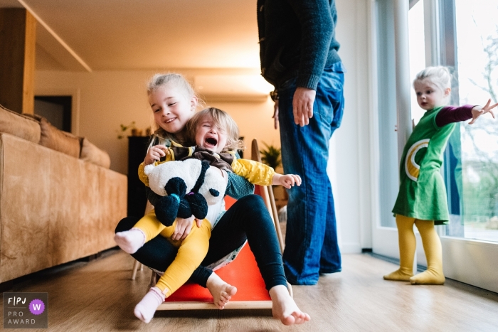 A little girl gets upset when her sister holds her as they go down a slide in this image created by a Gelderland, Netherlands family photographer.