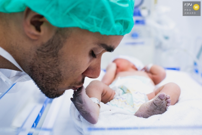 Photo by: <a href="https://www.fpja.com/documentary-family-photography-contests/ana-paula-faria/s%C3%A3o-paulo/2090071">Ana Paula Faria - Brazil</a> A father kisses his newborn baby's foot in the hospital in this award-winning birth photo by a Sao Paulo, Brazil photographer.