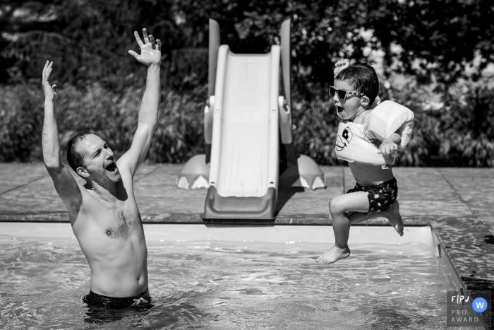 A father cheers as his little boy jumps into the pool in this FPJA award-winning picture by a Nantes family photographer.