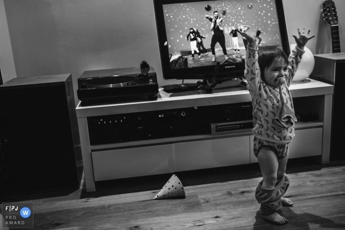 Une petite fille jette les mains en l'air avec enthousiasme alors que son pantalon tombe accidentellement dans cette photo primée de l'Association des photojournalistes de famille par un photographe de famille documentaire d'Anvers.