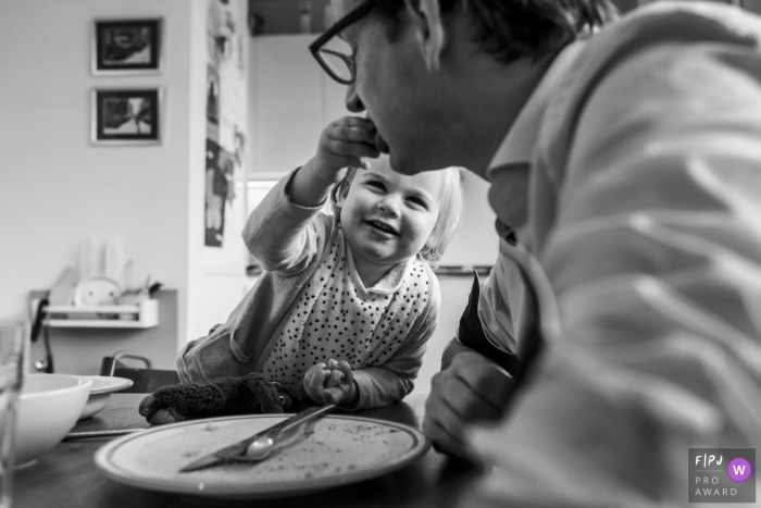 Photo by: <a href="https://www.fpja.com/documentary-family-photography-contests/gonda-meurs/noord-holland/2091566">Gonda Meurs - Netherlands</a> A little girl feeds her father in this award-winning photo by a Netherlands family photographer.
