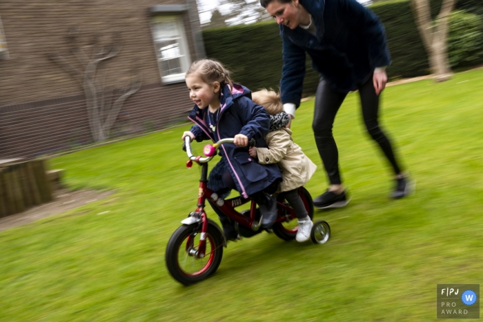 Photo by: <a href="https://www.fpja.com/documentary-family-photography-contests/gonda-meurs/noord-holland/2091651">Gonda Meurs - Netherlands</a> A mother helps her two young daughters ride a bike in this photo by a Netherlands award-winning family photographer.