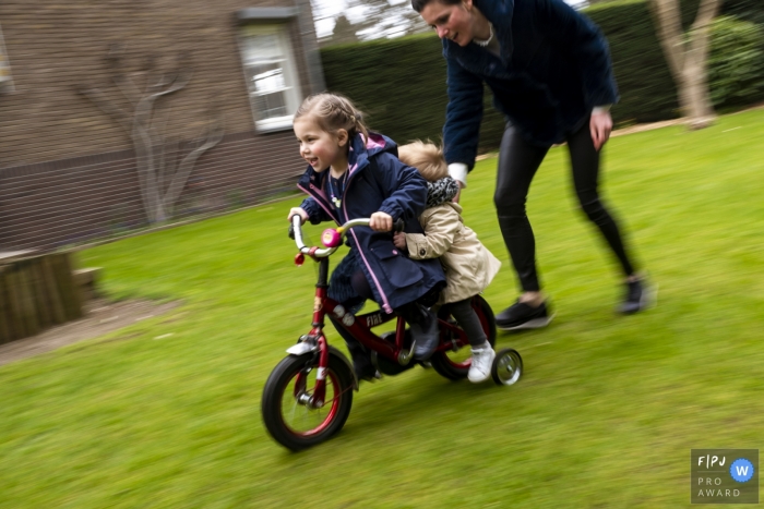 Une mère aide ses deux jeunes filles à faire du vélo sur cette photo d'un photographe de famille néerlandais primé.