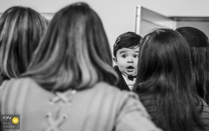 A little boy looks surprised as his family surrounds him in this Family Photojournalist Association awarded photo by an Arapongas documentary family photographer.