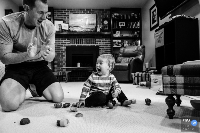 Un bébé garçon rit alors que son père applaudit sur cette photo prise par un photographe de famille primé à Boulder, CO.