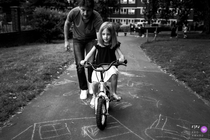 Photo by: <a href="https://www.fpja.com/documentary-family-photography-contests/ana-ruivo/london/2092956">Ana Ruivo - United Kingdom</a> A father helps his daughter learn to ride a bike in this photograph created by a London, England family photojournalist.