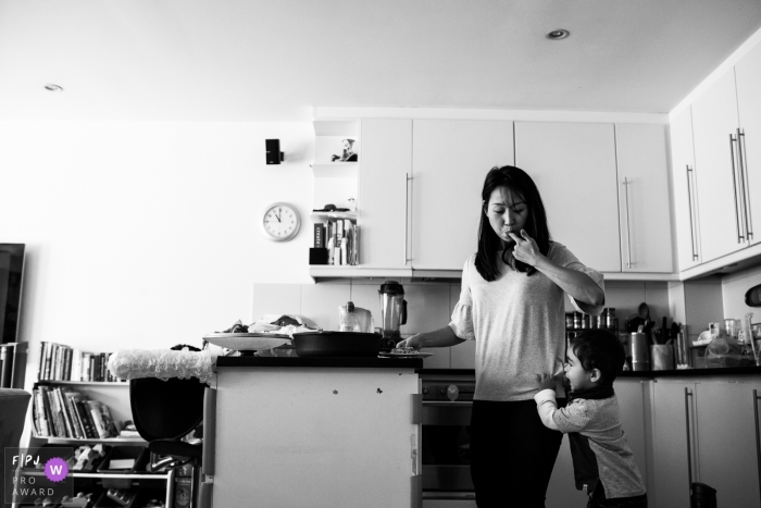 Un petit garçon regarde sa mère cuisiner dans la cuisine dans le cadre de ce concours de photojournaliste de la famille récompensé par une photo créée par un photographe de famille de Londres, en Angleterre.