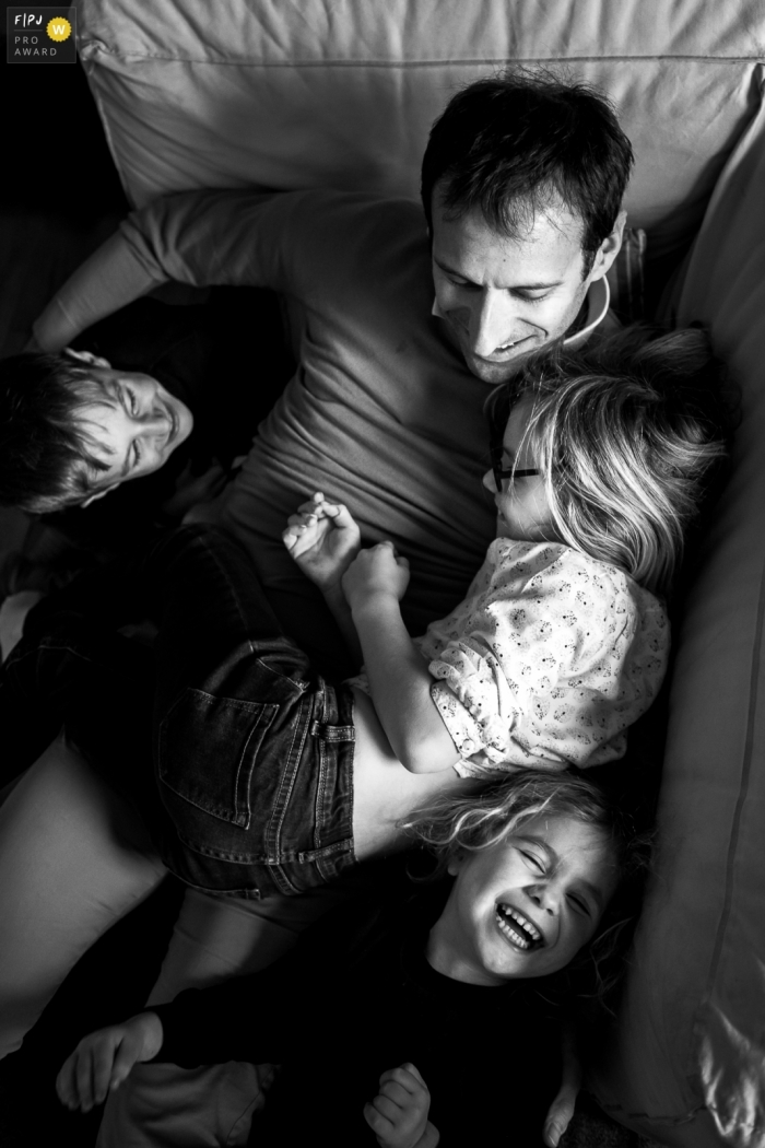 A father lays on the couch with his children in this FPJA award-winning picture by a London, England family photographer.