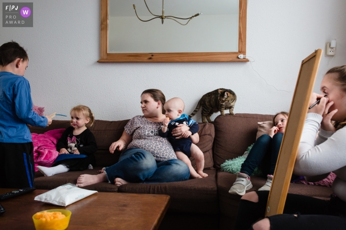 Une famille assise sur le canapé joue, se détend et se maquille dans cette photo de famille réalisée par un photographe néerlandais.