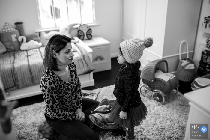 Une petite fille sourit à sa mère qui l'a habillée de vêtements d'hiver avec cette image primée au FPJA, capturée par un photographe de famille d'Essex, en Angleterre.