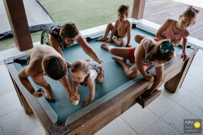 Photo by: <a href="https://www.fpja.com/documentary-family-photography-contests/thiago-braga/florianopolis/2093701">Thiago Braga - Brazil</a> A group of kids plays on top of a pool table in this FPJA award-winning picture by a Florianopolis family photographer.