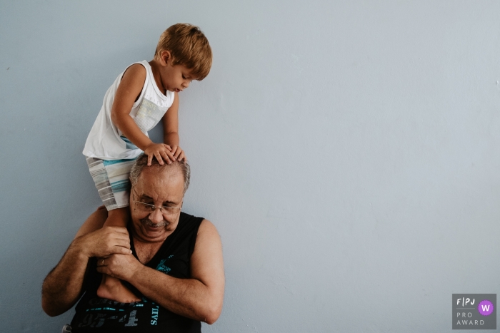 Photo by: <a href="https://www.fpja.com/documentary-family-photography-contests/thiago-braga/florianopolis/2093751">Thiago Braga - Brazil</a> A grandfather holds his grandson on his shoulder in this Family Photojournalist Association awarded photo by a Florianopolis documentary family photographer.