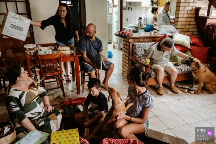 A family gathers together to open presents and enjoy cake in this FPJA award-winning image captured by a Florianopolis family photographer. 