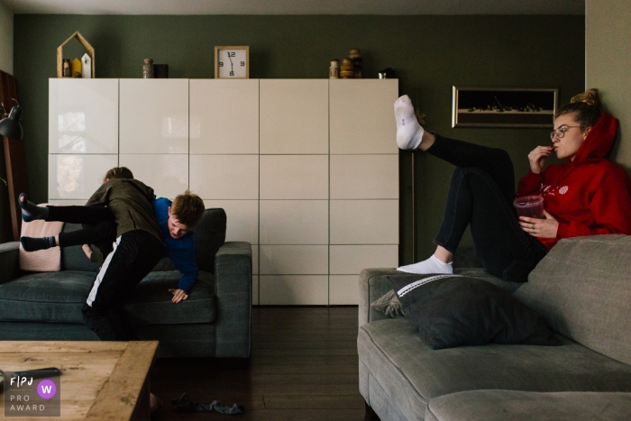 Photo by: <a href="https://www.fpja.com/documentary-family-photography-contests/liesbeth-parlevliet/zuid-holland/2095281">Liesbeth Parlevliet - Netherlands</a> Two boys wrestle on the sofa as their sister watches from the couch in this documentary-style family photo captured by a Netherlands photographer.