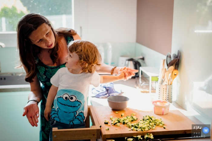 A mother scolds her son for making a mess in the kitchen as she tries to cook in this image created by a Haute-Garonne family photographer.