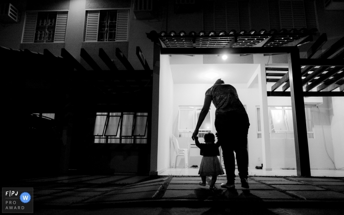 A mother helps her baby girl walk in this FPJA award-winning image captured by a Cuiaba family photographer. 