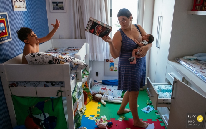Photo by: <a href="https://www.fpja.com/documentary-family-photography-contests/lisandro-castro/cuiab%C3%A1/2096391">Lisandro Castro - Brazil</a> A mother feeds her baby as she takes a toy away from her other son in this photo recorded by a Cuiaba award-winning, documentary-style family photographer.