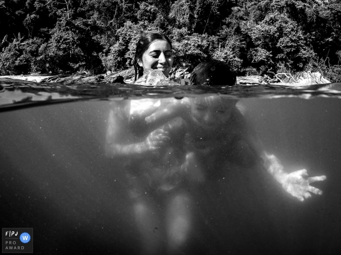 Auf diesem Foto eines preisgekrönten Familienfotografen aus Florianopolis schwimmen eine Mutter und ihr Sohn gemeinsam in einem See.