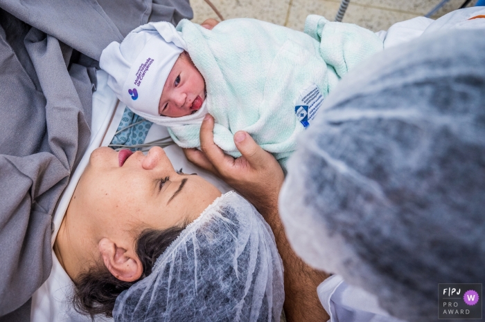 Photo by: <a href="https://www.fpja.com/documentary-family-photography-contests/ta%C3%ADs-motta/campinas/2096751">Taís Motta - Brazil</a> A nurse brings a baby over to its mother to see for the first time in this image composed by an award-winning Campinas birth photographer.