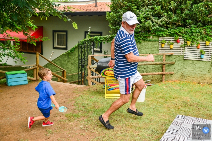 Photo by: <a href="https://www.fpja.com/documentary-family-photography-contests/vinicius-fadul/campinas/2096756">Vinicius Fadul - Brazil</a> A grandson chases his grandfather outside in this Family Photojournalist Association contest awarded photo created by a Campinas family photographer.