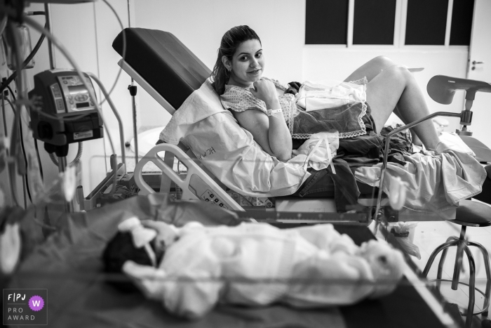 This black and white photo of a mother admiring her newborn daughter across the hospital room was captured by a Brazil documentary family photographer 