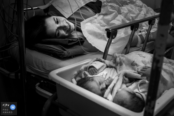 Photo by: <a href="https://www.fpja.com/documentary-family-photography-contests/gabi-marques/minas-gerais/2097376">Gabi Marques - Brazil</a> Brazil documentary family photographer captured this black and white image of a mother lovingly looking at her newborn twins who are resting in a bassinet beside her hospital bed