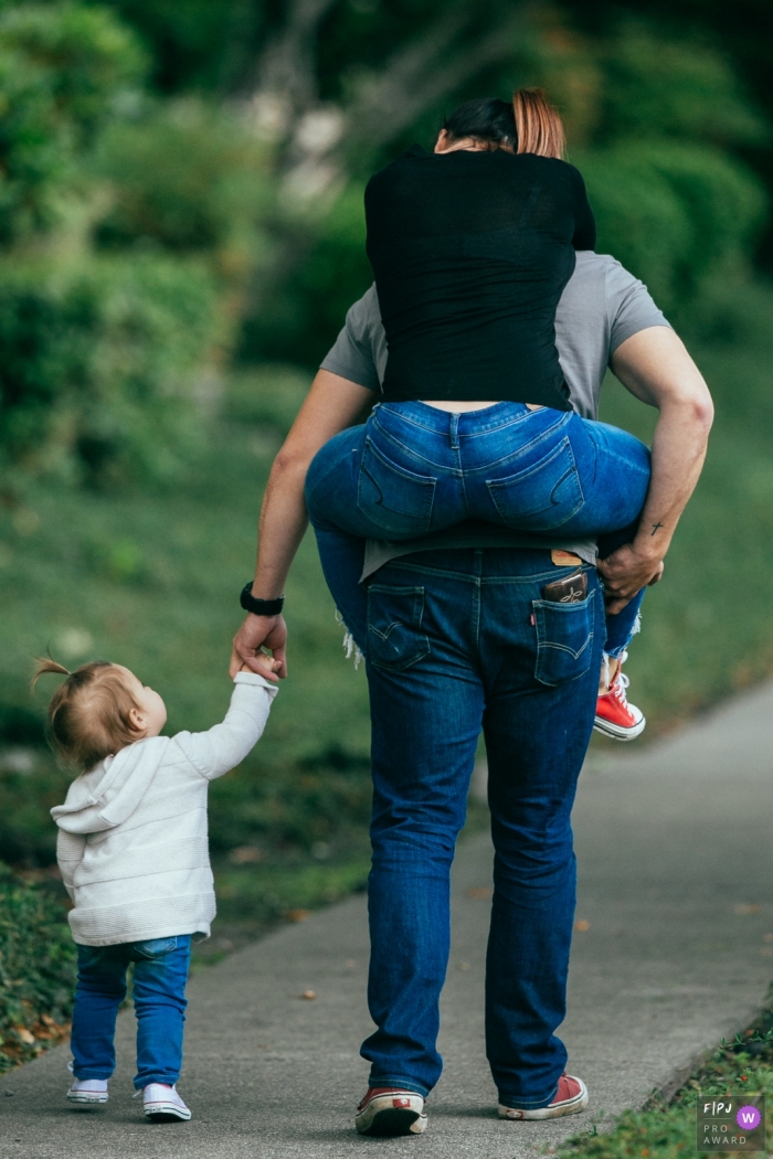 Une femme chevauche le dos de son mari alors qu'ils marchent avec leur fille sur cette photo prise par un photojournaliste de la famille de Seattle, WA.