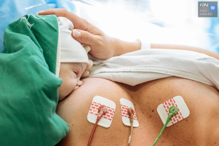 A mother breast feeds her newborn in the hospital for the first time in this birth photo by a documentary-style Rio de Janeiro, Brazil photographer.