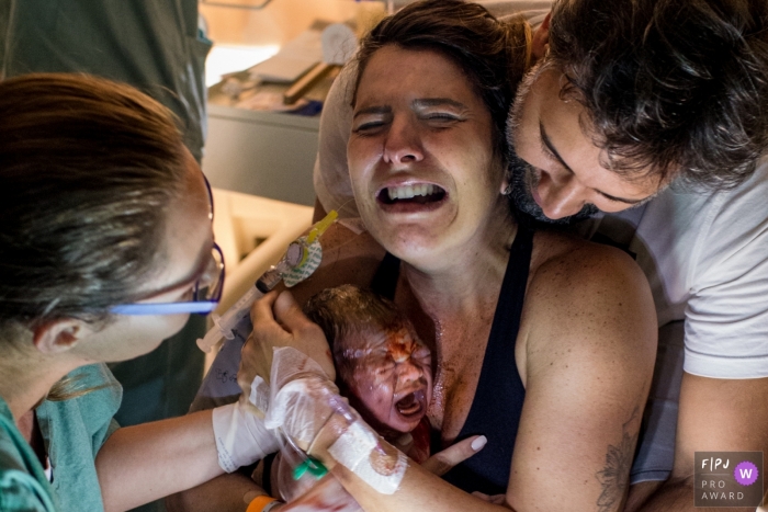 A mother cries tears of joy as she holds her infant for the first time in the hospital in this photo taken by a Sao Paulo, Brazil birth photographer.