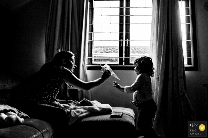 Photo by: <a href="https://www.fpja.com/documentary-family-photography-contests/rafael-rosa/rio-grande-do-sul/2098076">Rafael Rosa - Brazil</a> A mother and daughter play with a paper airplane in this Family Photojournalist Association contest awarded photo created by a Rio Grande do Sul, Brazil family photographer.