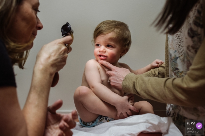 Photo by: <a href="https://www.fpja.com/documentary-family-photography-contests/meg-brock/philadelphia/2098346">Meg Brock - United States</a> A mom holds her son as the doctor checks his eyes in this picture captured by a Philadelphia family photojournalist.